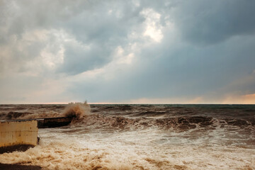 Storm waves near the shore on the beach. In the foreground, breakwaters.