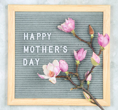 letterboard with white plastic letters with quote Happy Mother's Day, and magnolia flowers on light background