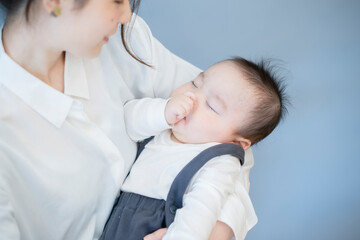 寝ている赤ちゃんを抱っこするお母さん