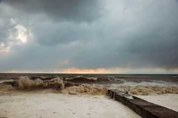 Storm waves near the shore on the beach. In the foreground, breakwaters.