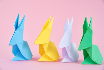 Paper colorful origami Esater rabbits on a pink background. Easter celebration concept