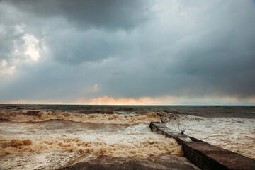 Storm waves near the shore on the beach. In the foreground, breakwaters.