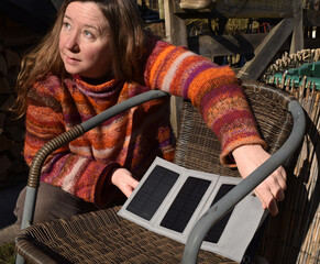 Frau Mitte 40 richtet Photovoltaik Panele auf Sonnenschein ein, Mini-PV-Anlage