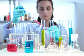 laboratory equipment, supplies, jars, bottles, cylinders, beakers, graduate, test-mixer, medicine-glass. Lab assistant holding petri dish, pipetting liquid in defocus