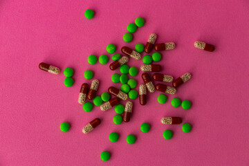 a bunch of different pills vitamins pills and capsules are lying on the table on a pink background close up view from above