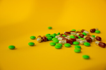 a bunch of different pills vitamins pills and capsules are lying on the table on a yellow background close up view from above