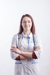 Portrait of a young female doctor in a white uniform who crossed her arms in the studio on a white background