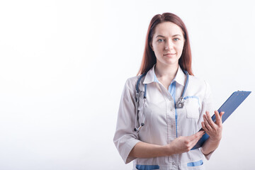 Portrait of a young female doctor in a white uniform with a folder in hands in the studio on a white background with copyspace