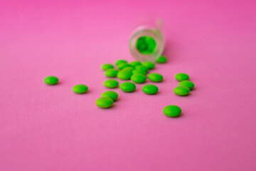 green pills on a pink background close up top view