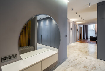 Interior of luxury house. Grey tones. Entrance hall. Round mirror.