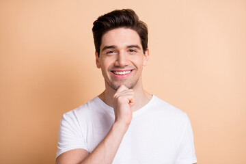 Photo of charming happy man hold hand chin think positive idea isolated on pastel beige color...