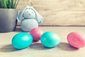 Toy Easter bunny and painted eggs on a wooden background.