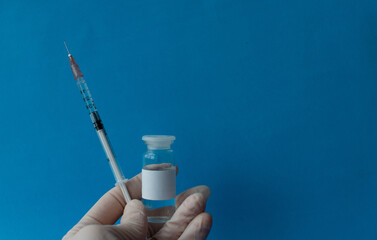 a syringe with a vaccine and ampoules with a vaccine against infections close-up on a blue...