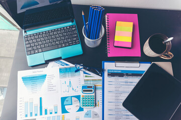 Office laptop business financial document chart and graph on wooden table with coffee cup. Flat lay notebook computer laptop on office desk. No people business graph chart mockup on business workspace