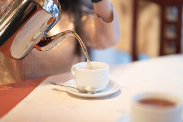 pours boiling water from a kettle. makes tea