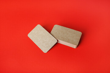 Photo of blank kraft business cards on red paper background. Branding ID template.