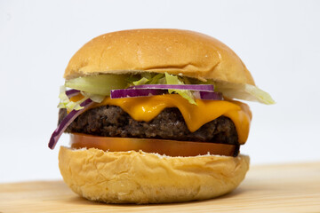 Gourmet cheese burger on a wooden board on white infinite background