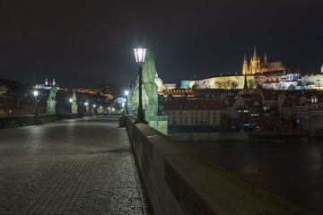 Fototapeta premium street light lantern on Charles Bridge and Prague Castle and St. Vitus Cathedral in the background at sunset