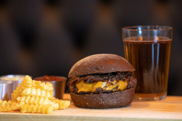 Gourmet cheeseburger with fries and soda in composition
