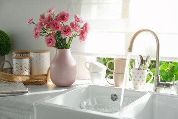 Vase with flowers on countertop near sink against window in kitchen