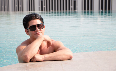 portarit handsome, muscular caucasian white man wearing sunglasses in a swimming pool summer vacation