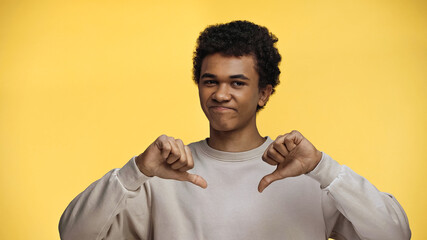 african american teenage boy showing dislike isolated on yellow