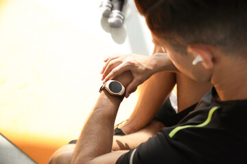 Man checking fitness tracker in gym, closeup