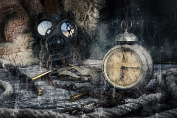 Vintage clock resting on wooden surface with military gas mask and rusty chains in background
