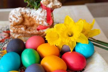Easter eggs in different color, yellow  daffodils, easter bunny and seasonal decoration on a table. Tradition and religion in Europe.
