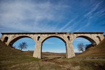 Fototapeta na wymiar Old destroyed narrow-gauge railway bridge of the arched type