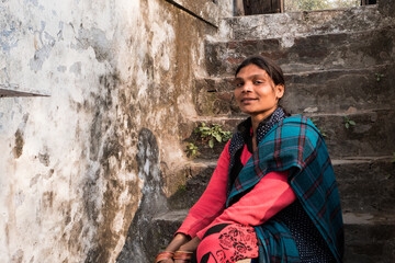 Fototapeta na wymiar A happy Indian woman smiles on the steps of the old temple. Travel to India. Native people