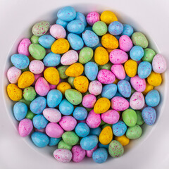 Pile of colorful shiny Easter eggs in a white round bowl 