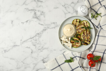 Flat lay composition with delicious grilled zucchini slices on white marble table, space for text