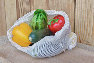 fresh vegetables in a reusable bag put on a wooden table