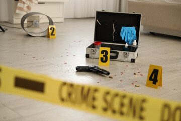 Crime scene markers, gun and criminologist case on floor in room