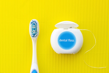 A blue toothbrush and dental floss on a yellow background. Healthcare concept. Oral hygiene