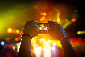 Hand with the smartphone turned on to record or take pictures during the live concert.