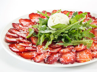 fruit salad with fresh sliced strawberries, arugula leaves and scoop of ice cream