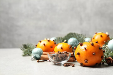 Delicious fresh tangerines with cloves on light table, space for text. Christmas celebration