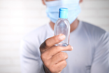  man in face mask holding sanitizer liquid 