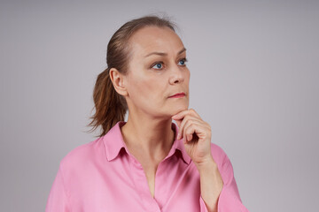 Senior business woman with ponytail hairstyle, in a pink blouse, with a serious expression....