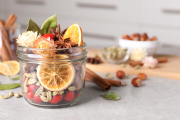 Aromatic potpourri in glass jar on light table. Space for text