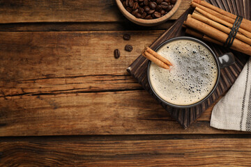 Cup of hot coffee with aromatic cinnamon on wooden table, flat lay. Space for text