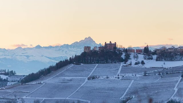 Pan: Italy Piedmont panoramic winter snow view wine yards unique landscape at sunset, Novello medieval castle and villages on hill top, the Alps in the background dramatic sky