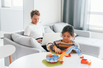 Single father with his daughter is at home together at daytime. Playing with toys