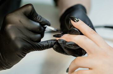 The manicure master in the beauty salon performs the procedure of coloring the client's nails....