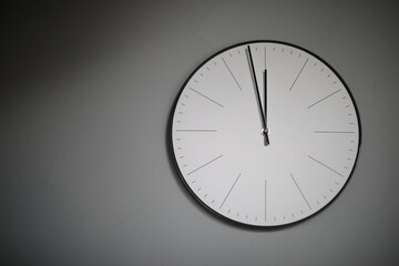 a large round white clock , on a gray wall
