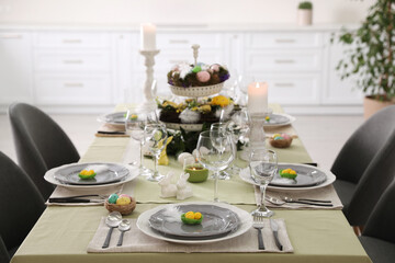 Beautiful Easter table setting with burning candles indoors