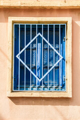 Blue wooden window with geometric iron lattice