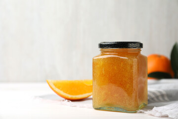 Delicious orange marmalade in jar on white table, space for text